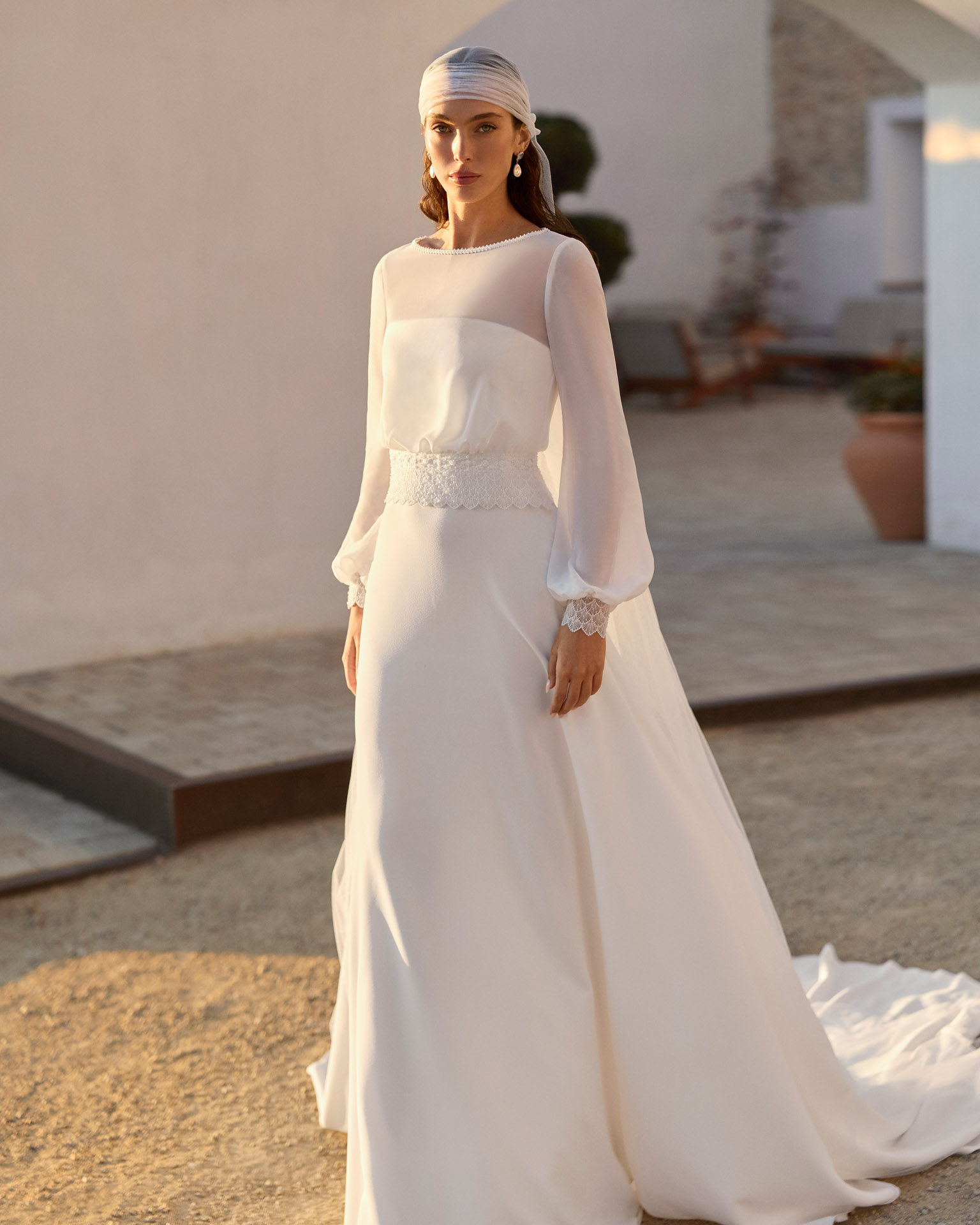 relia-vestido-novia-mangas-largas-gasa-estilo-minimalista-aire-barcelona-2027.delante Vestido de novia Relia de Aire Barcelona 2027 con mangas largas de gasa transparente, escote barco, cintura de encaje, falda fluida de crepé y elegante espalda cerrada.