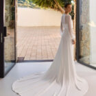 Vestido de novia Relia de Aire Barcelona 2027 con mangas largas de gasa transparente, escote barco, cintura de encaje, falda fluida de crepé y elegante espalda cerrada.