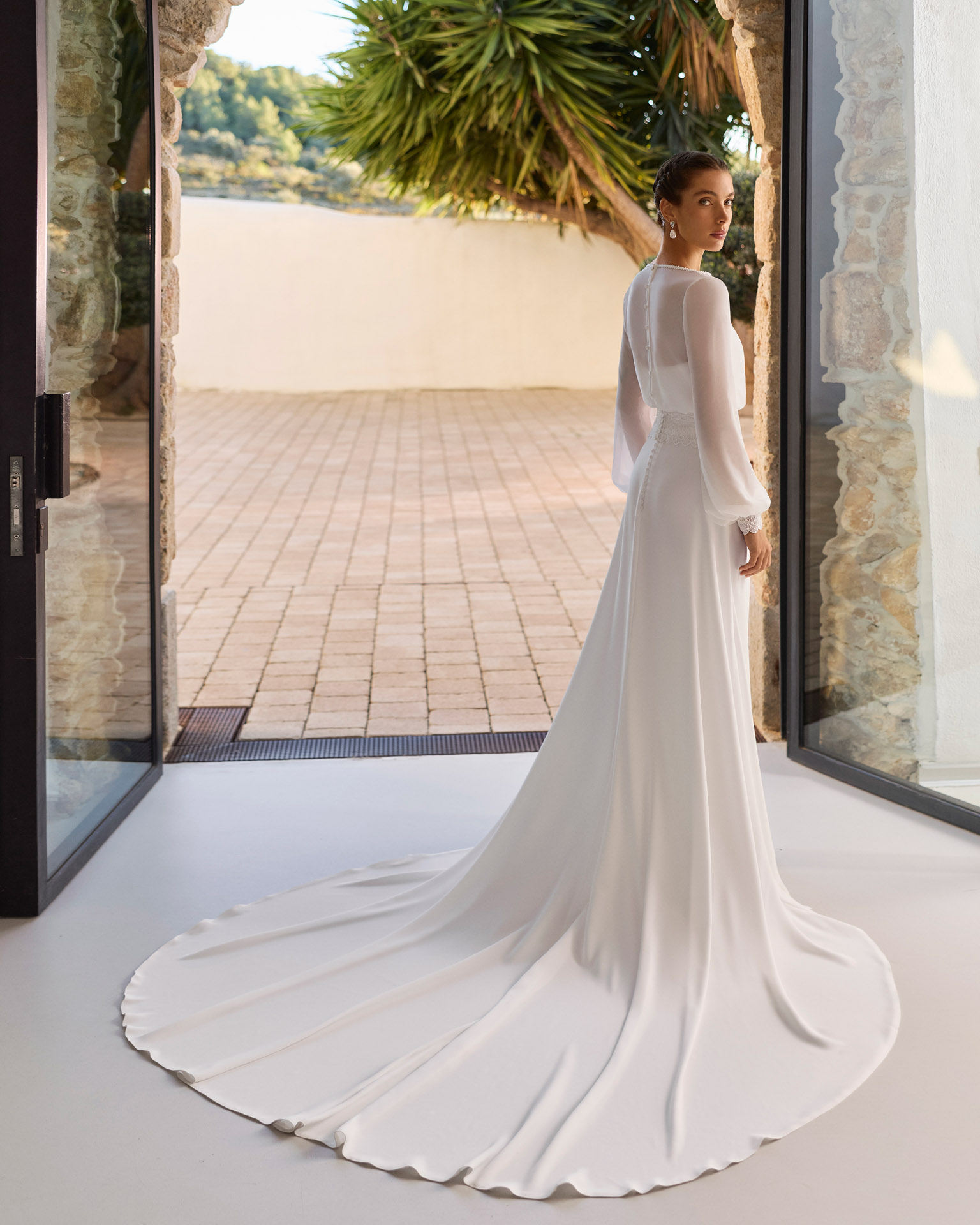 Vestido de novia Relia de Aire Barcelona 2027 con mangas largas de gasa transparente, escote barco, cintura de encaje, falda fluida de crepé y elegante espalda cerrada.