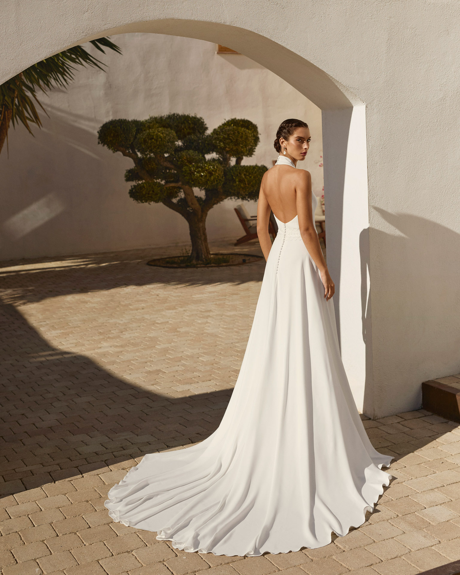 Vestido de novia Renys de Aire Barcelona 2027 en crepé con escote halter, espalda descubierta, cintura bordada y falda de caída fluida.