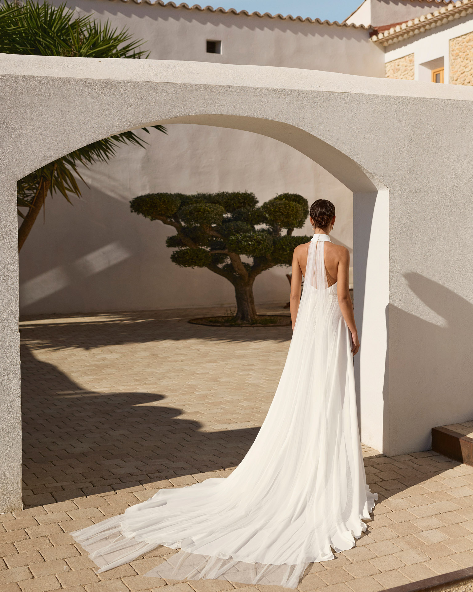 Vestido de novia Renys de Aire Barcelona 2027 en crepé con escote halter, espalda descubierta, cintura bordada y falda de caída fluida.
