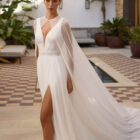 Vestido de novia Riga de Aire Barcelona 2027 de corte A en gasa plisada con escote en pico, espalda en V, abertura frontal y capa de gasa.