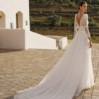 Vestido de novia Rin de Aire Barcelona 2027 de línea A con cuerpo de encaje floral, escote en V, espalda abierta, falda plisada de tul con abertura lateral y cola ligera.