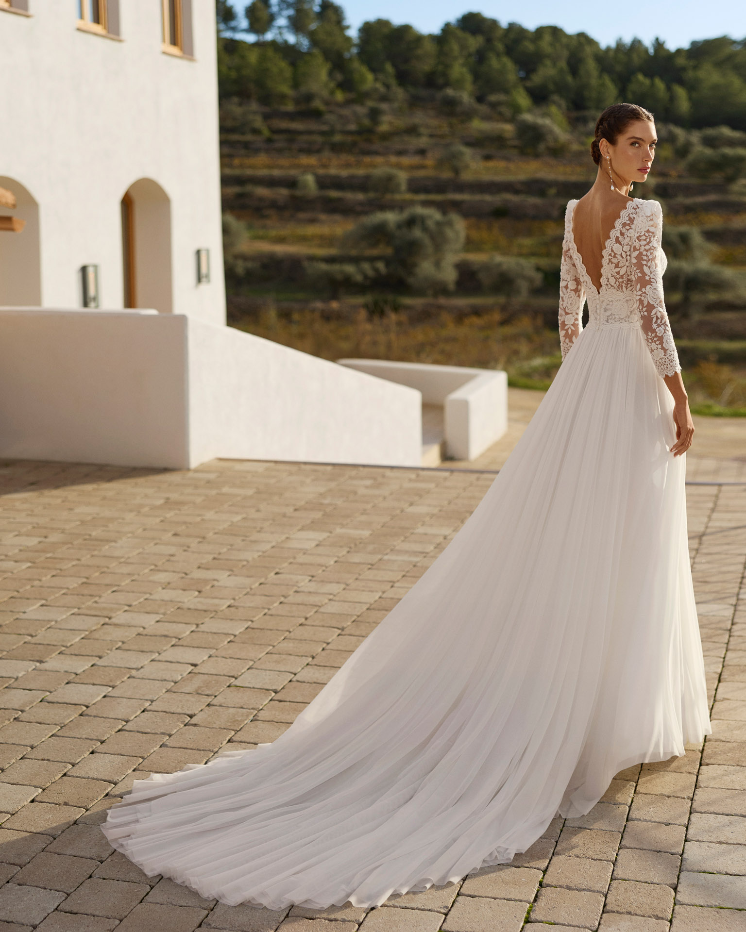 Vestido de novia Rin de Aire Barcelona 2027 de línea A con cuerpo de encaje floral, escote en V, espalda abierta, falda plisada de tul con abertura lateral y cola ligera.