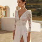 Vestido de novia Rin de Aire Barcelona 2027 de línea A con cuerpo de encaje floral, escote en V, espalda abierta, falda plisada de tul con abertura lateral y cola ligera.