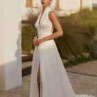Vestido de novia Rinlo de Aire Barcelona 2027 de corte A en gasa plisada con escote halter de encaje, cuerpo semitransparente, abertura en la falda y espalda de encaje.