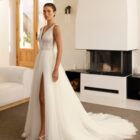 Vestido de novia Riosa de Aire Barcelona 2027 de corte A en tul con escote en pico, cuerpo de encaje floral, espalda en V, abertura frontal y detalle floral en la espalda.