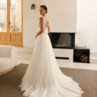 Vestido de novia Riosa de Aire Barcelona 2027 de corte A en tul con escote en pico, cuerpo de encaje floral, espalda en V, abertura frontal y detalle floral en la espalda.