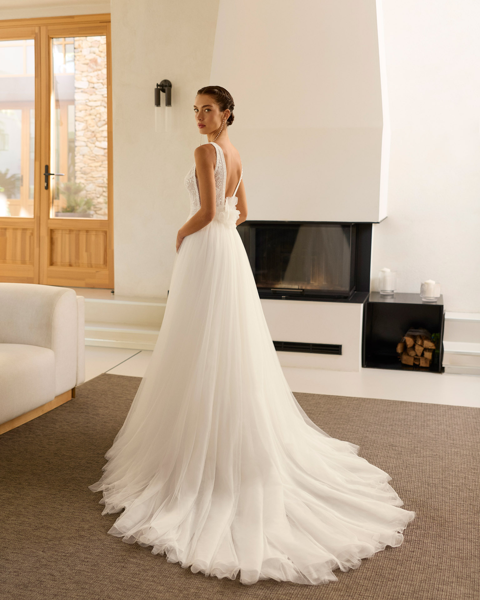 Vestido de novia Riosa de Aire Barcelona 2027 de corte A en tul con escote en pico, cuerpo de encaje floral, espalda en V, abertura frontal y detalle floral en la espalda.