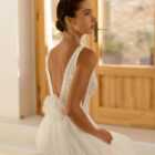 Vestido de novia Riosa de Aire Barcelona 2027 de corte A en tul con escote en pico, cuerpo de encaje floral, espalda en V, abertura frontal y detalle floral en la espalda.