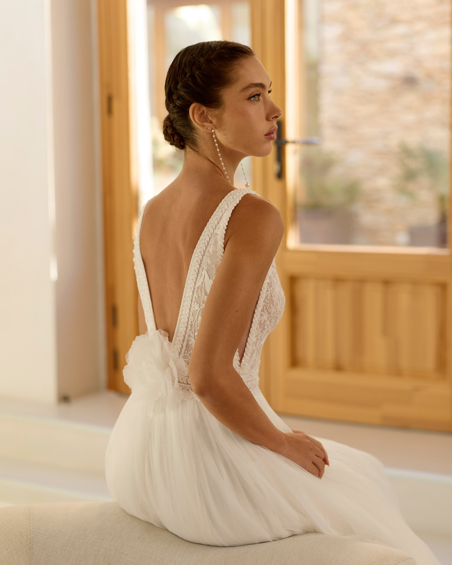 Vestido de novia Riosa de Aire Barcelona 2027 de corte A en tul con escote en pico, cuerpo de encaje floral, espalda en V, abertura frontal y detalle floral en la espalda.
