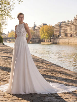 Vestido de novia Tatiana de Aire Barcelona 2027 de línea A con cuerpo de encaje floral, escote caja, espalda abierta con cadenas joya y falda vaporosa con cola de encaje.