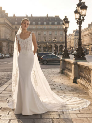 Vestido de novia Teline de Aire Barcelona 2027 de corte sirena en crepé, cuerpo de encaje bordado, escote redondeado y elegante cola de tul con aplicaciones florales.