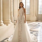 Vestido de novia Aire Barcelona 2027 con escote halter de encaje floral, falda de tul y silueta línea A de estilo romántico.