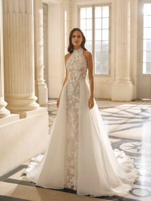 Vestido de novia Aire Barcelona 2027 con escote halter de encaje floral, falda de tul y silueta línea A de estilo romántico.
