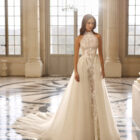 Vestido de novia Aire Barcelona 2027 con escote halter de encaje floral, falda de tul y silueta línea A de estilo romántico.