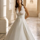 Vestido de novia Aire Barcelona 2027 de mikado con escote pico, cuerpo de encaje floral y falda evasé de estilo clásico y elegante.