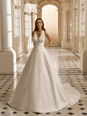 Vestido de novia Aire Barcelona 2027 de mikado con escote pico, cuerpo de encaje floral y falda evasé de estilo clásico y elegante.