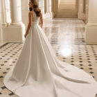 Vestido de novia Aire Barcelona 2027 de mikado con escote pico, cuerpo de encaje floral y falda evasé de estilo clásico y elegante.