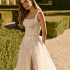 Vestido de novia Xenea de Aire Barcelona 2027 de corte A en tul bordado con escote cuadrado, cuerpo de encaje floral, abertura frontal y capa de tul integrada.