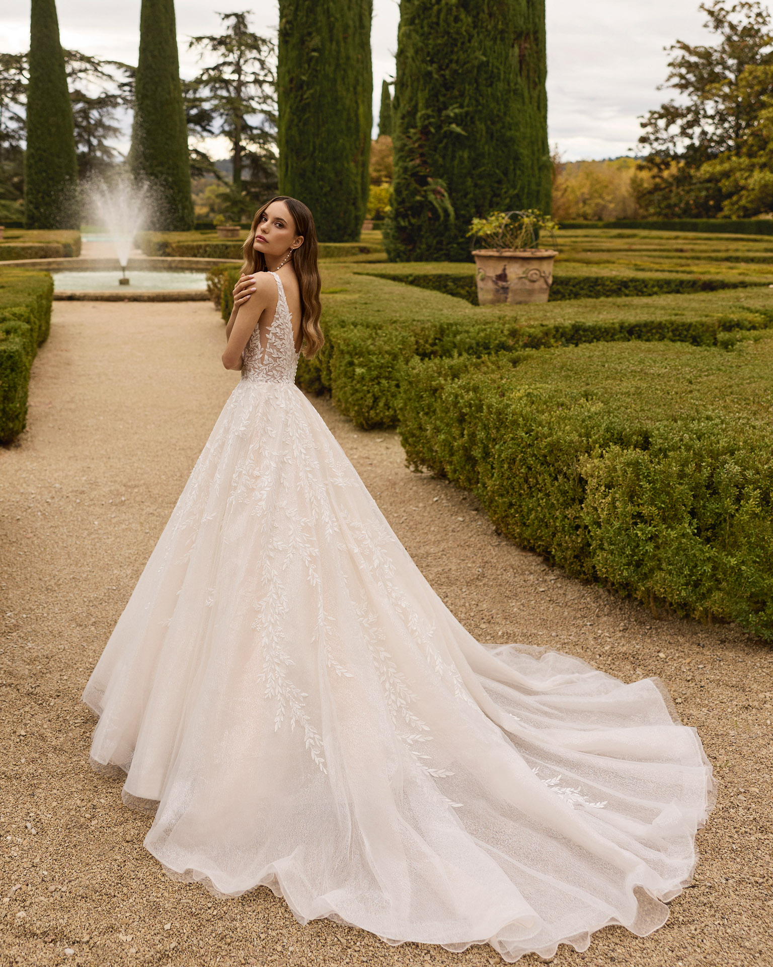 Vestido de novia Xiona de Aire Barcelona 2027 de corte princesa con escote en V, cuerpo de encaje floral, espalda descubierta y amplia falda de tul con brillo.