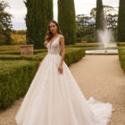 Vestido de novia Xiona de Aire Barcelona 2027 de corte princesa con escote en V, cuerpo de encaje floral, espalda descubierta y amplia falda de tul con brillo.