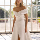 Vestido de novia Forbia de Luna Novias con escote de hombros descubiertos y falda con abertura