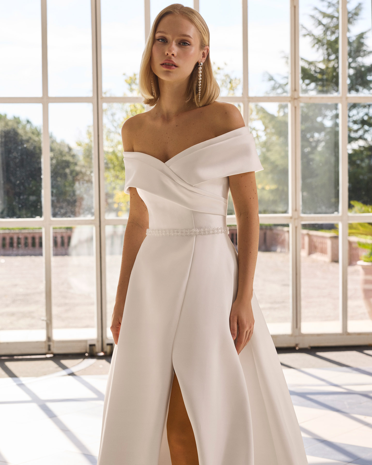 Vestido de novia Forbia de Luna Novias con escote de hombros descubiertos y falda con abertura