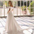 Vestido de novia Forbia de Luna Novias con escote de hombros descubiertos y falda con abertura