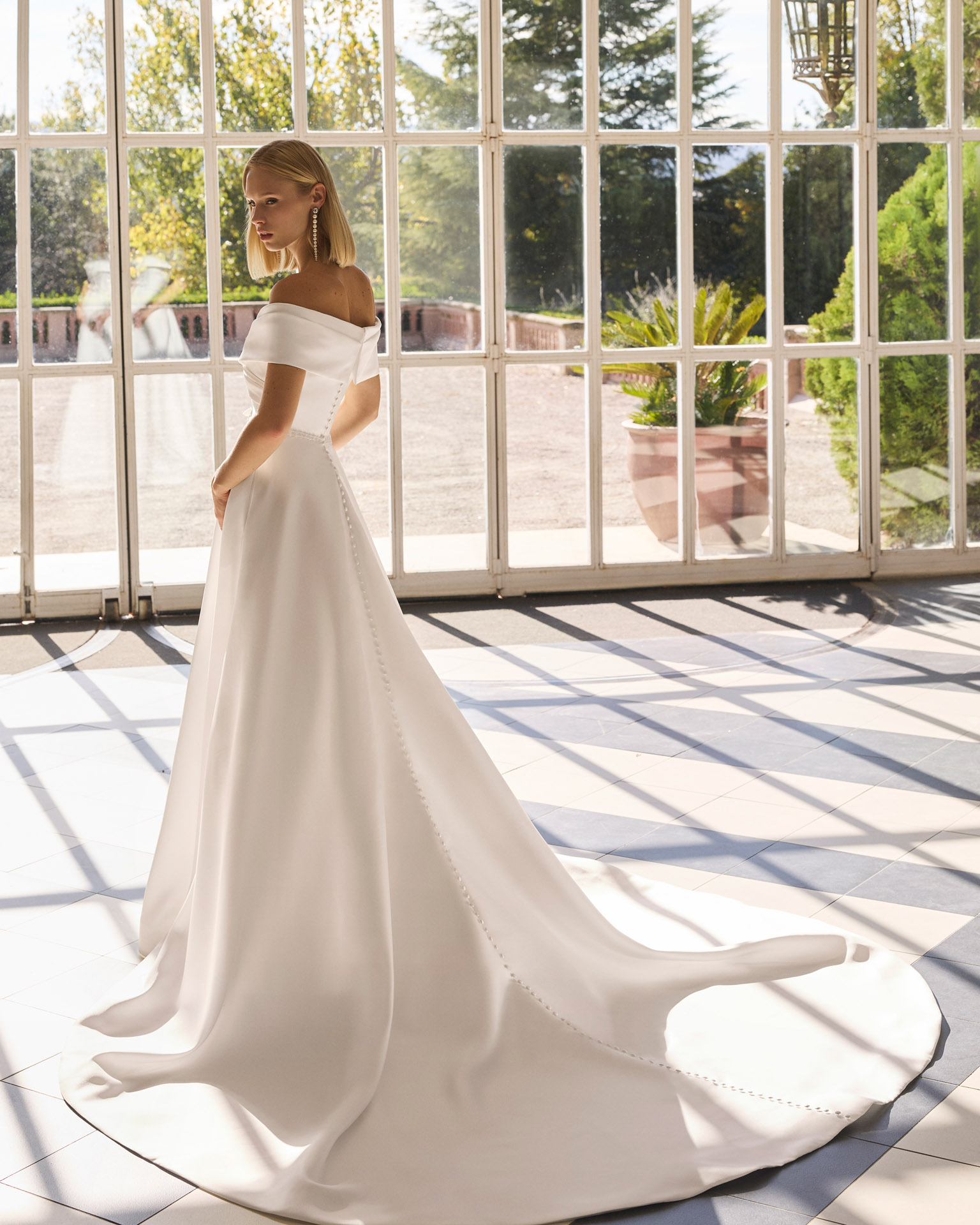 Vestido de novia Forbia de Luna Novias con escote de hombros descubiertos y falda con abertura