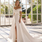 Vestido de novia Forbia de Luna Novias con escote de hombros descubiertos y falda con abertura