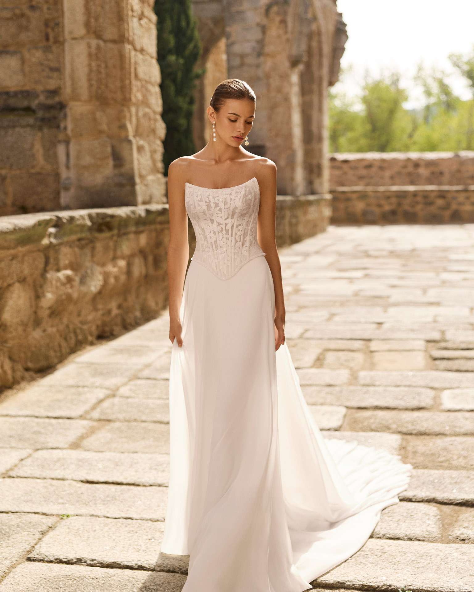 Vestido de novia Portia de Adriana Alier con corsé de encaje floral, hombros descubiertos y falda fluida