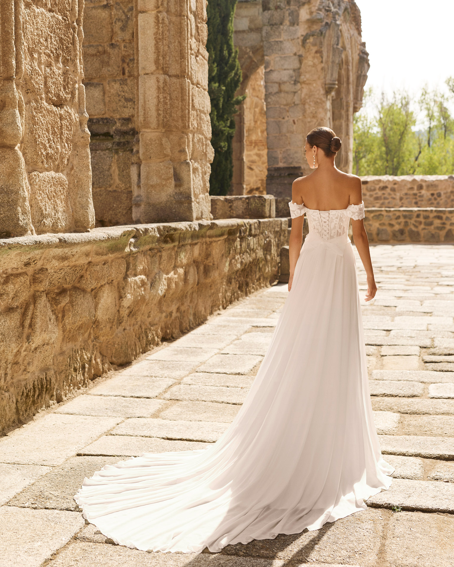 Vestido de novia Portia de Adriana Alier con corsé de encaje floral, hombros descubiertos y falda fluida